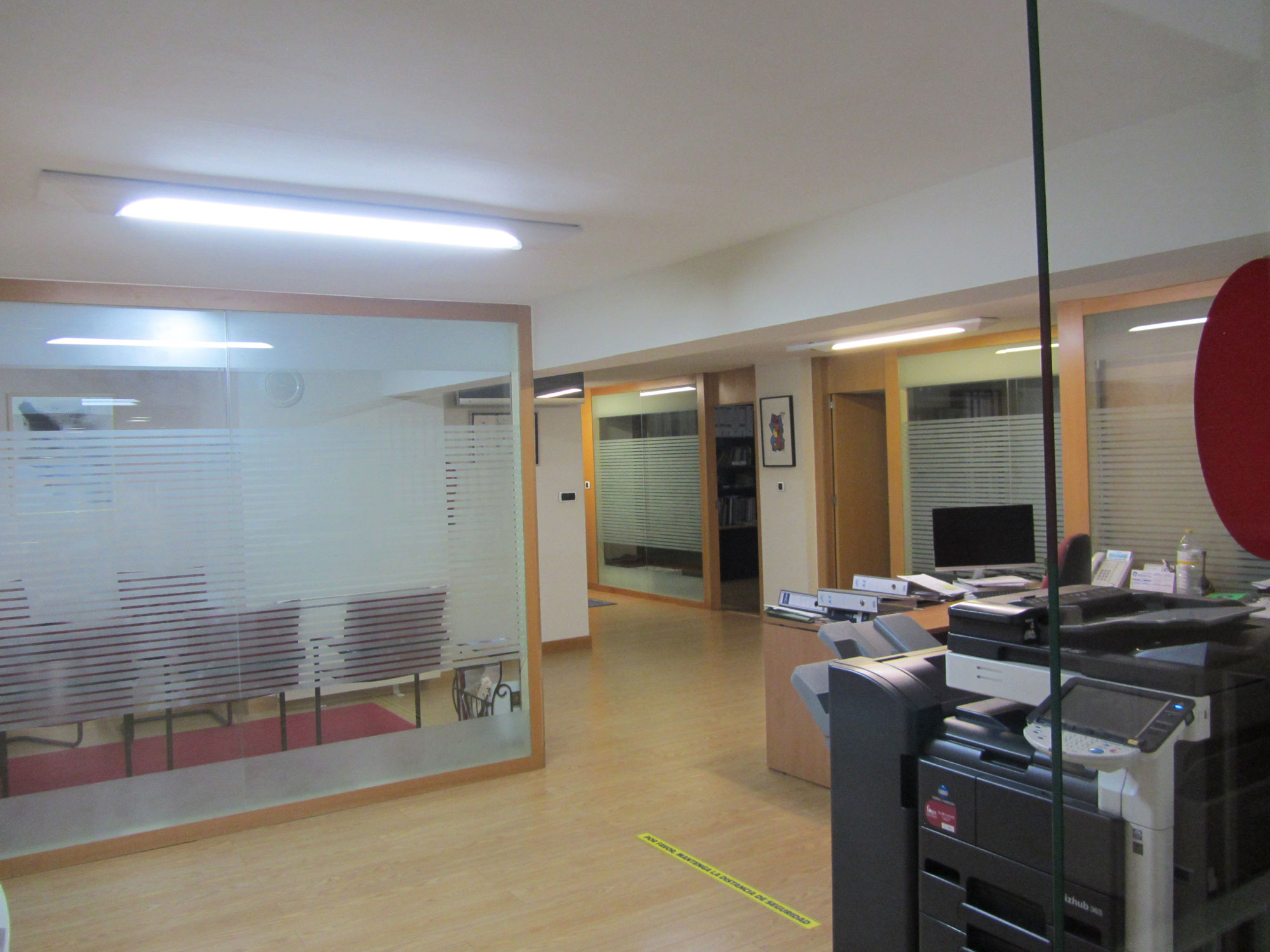 Instalaciones de ESES Galicia, despachos acristalados, suelo de madera y se ve la recepción y la fotocopiadora