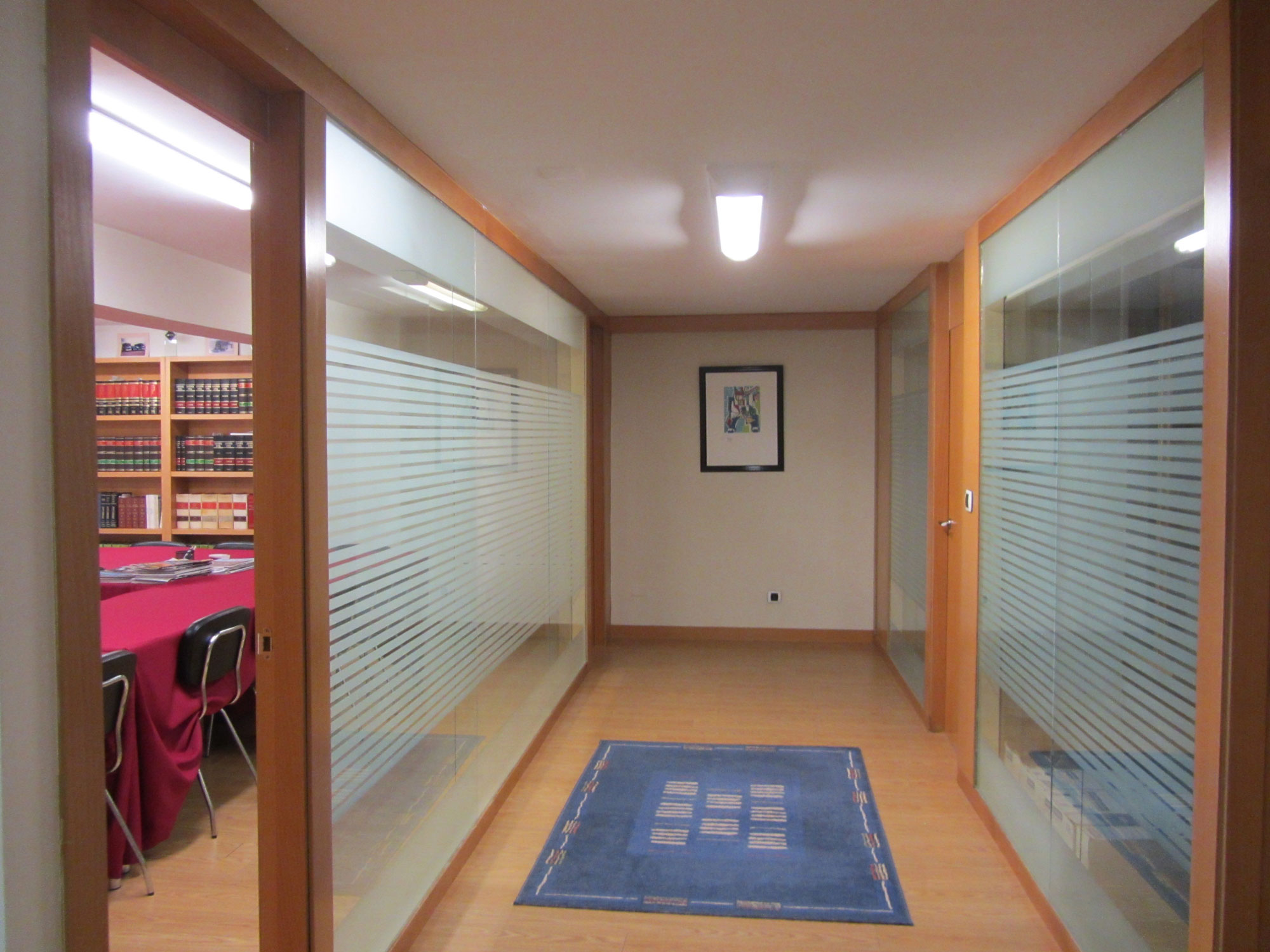 oficinas de Eses Galicia, suelo de madera, paredes acristaladas y se ve una sala con una mesa grande y estanterías llenas de libros